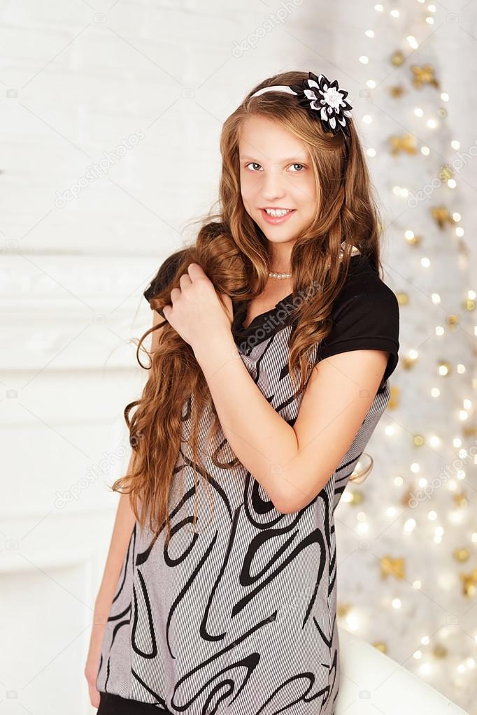 Portrait of pretty long-haired smiling teen girl in dress in int