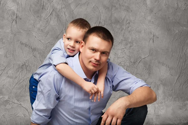 Padre e figlioletto in camicie blu davanti a sfondo grigio — Foto Stock