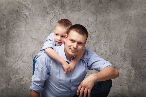 Vader en zoontje voor grijze achtergrond — Stockfoto