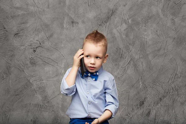 Portrait of a cute little boy in blue shirt and bow tie with mob — Stock Photo, Image