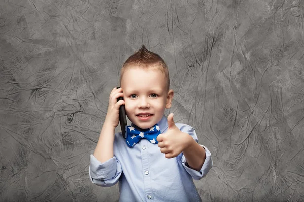 Portret van een schattige kleine jongen in het blauwe shirt en strikje met menigte — Stockfoto
