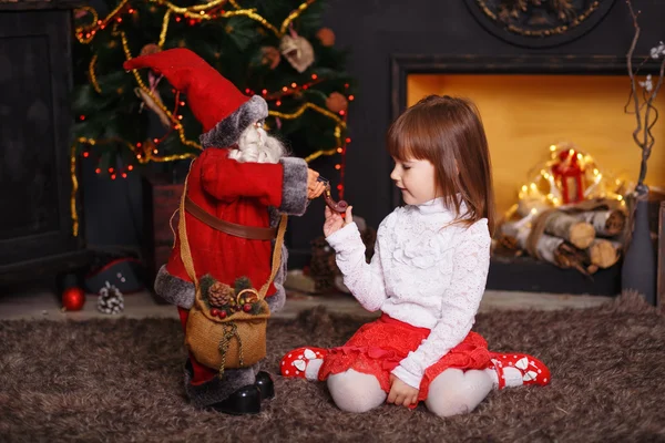 Kleines Mädchen spielt mit einem Spielzeug Weihnachtsmann. — Stockfoto