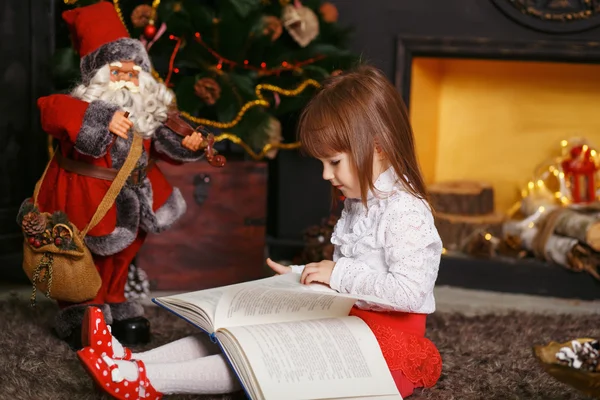 Дівчина, читаючи казку іграшки Санта-Клауса — стокове фото