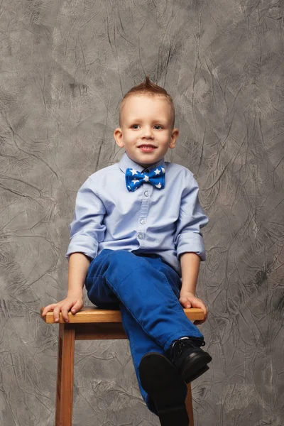 Retrato de um menino engraçado sentado em um banquinho alto — Fotografia de Stock