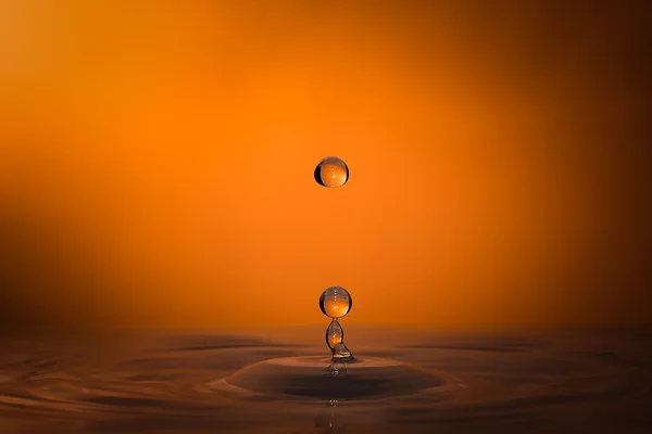Spadających kropli wody na pomarańczowym tle — Zdjęcie stockowe