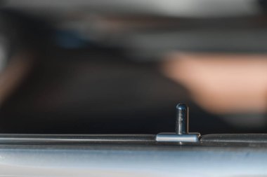 Araba kapısının kenarında metal bir pim ya da kilit kilidi var. Bitişi mat olan Black Metal 'den yapılmış. Detaylar net bir şekilde odaklanmış durumda. Arka plan çok bulanık..