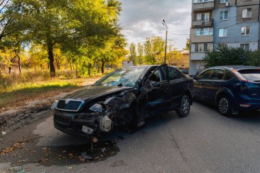 Trafik kazasından sonra ağır hasar görmüş siyah bir arabanın yakın çekimi. Ön tarafı tamamen ezilmiş, şiddetli vücut deformasyonuyla. Tekerlek hizalanmamış..
