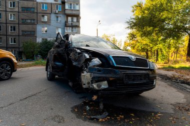Trafik kazasından sonra ağır hasar görmüş siyah bir arabanın yakın çekimi. Ön tarafı tamamen ezilmiş, şiddetli vücut deformasyonuyla. Tekerlek hizalanmamış..