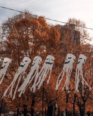 Çerçeveden geçen bir dizi beyaz hayaletin ritmik olarak düzenlendiği şık bir kompozisyon. Cadılar Bayramı, sonbahar, sokak dekorasyonu, tatil etkinlikleri ve park tasarımı için mükemmel..