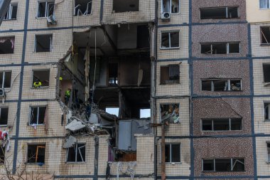 Bir apartman binasının ön cephesinin bir parçası. Patlama ya da bombardıman sonucu oluşan büyük hasarı gösteriyor. Duvardaki gedik birkaç kat boyunca uzanıyor ve yıkılan iç mekanı ortaya çıkarıyor..