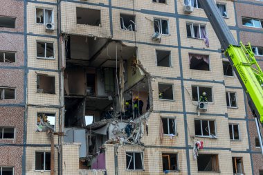 Bir apartman binasının ön cephesinin bir parçası. Patlama ya da bombardıman sonucu oluşan büyük hasarı gösteriyor. Duvardaki gedik birkaç kat boyunca uzanıyor ve yıkılan iç mekanı ortaya çıkarıyor..