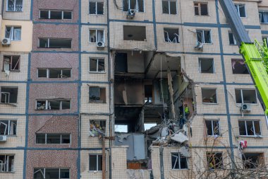 Bir apartman binasının ön cephesinin bir parçası. Patlama ya da bombardıman sonucu oluşan büyük hasarı gösteriyor. Duvardaki gedik birkaç kat boyunca uzanıyor ve yıkılan iç mekanı ortaya çıkarıyor..