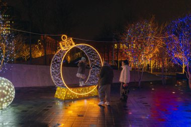 Gece aydınlatması: kış tatilleri boyunca parlak ve dekore edilmiş bir şehir caddesi. Çok renkli LED ışıklar ve dekorasyonlar. İnsanlar şehir merkezinde dolaşırken neşeli bir atmosfer..