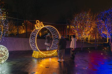 Gece aydınlatması: kış tatilleri boyunca parlak ve dekore edilmiş bir şehir caddesi. Çok renkli LED ışıklar ve dekorasyonlar. İnsanlar şehir merkezinde dolaşırken neşeli bir atmosfer..