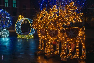 Gece aydınlatması: kış tatilleri boyunca parlak ve dekore edilmiş bir şehir caddesi. Çok renkli LED ışıklar ve dekorasyonlar. İnsanlar şehir merkezinde dolaşırken neşeli bir atmosfer..