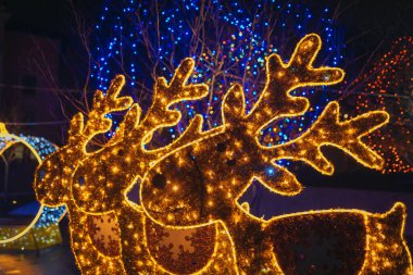 Gece aydınlatması: kış tatilleri boyunca parlak ve dekore edilmiş bir şehir caddesi. Çok renkli LED ışıklar ve dekorasyonlar. İnsanlar şehir merkezinde dolaşırken neşeli bir atmosfer..