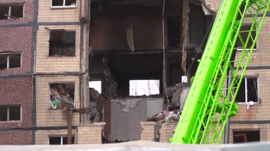 Bir apartman binasının ön cephesinin bir parçası. Patlama ya da bombardıman sonucu oluşan büyük hasarı gösteriyor. Duvardaki gedik birkaç kat boyunca uzanıyor ve yıkılan iç mekanı ortaya çıkarıyor..