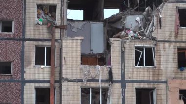 Bir apartman binasının ön cephesinin bir parçası. Patlama ya da bombardıman sonucu oluşan büyük hasarı gösteriyor. Duvardaki gedik birkaç kat boyunca uzanıyor ve yıkılan iç mekanı ortaya çıkarıyor..