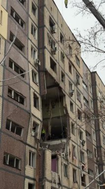 Bir apartman binasının ön cephesinin bir parçası. Patlama ya da bombardıman sonucu oluşan büyük hasarı gösteriyor. Duvardaki gedik birkaç kat boyunca uzanıyor ve yıkılan iç mekanı ortaya çıkarıyor..