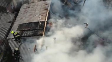 Özel bir yerleşim bölgesinde yangın: özel evlerin çatılarından yoğun beyaz duman yükseliyor. Olay yeri görüntüsü (drone). İtfaiye ekipleri: Yanan çatıda, yangından geriye kalanlar..