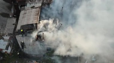 Özel bir yerleşim bölgesinde yangın: özel evlerin çatılarından yoğun beyaz duman yükseliyor. Olay yeri görüntüsü (drone). İtfaiye ekipleri: Yanan çatıda, yangından geriye kalanlar..