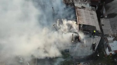 Özel bir yerleşim bölgesinde yangın: özel evlerin çatılarından yoğun beyaz duman yükseliyor. Olay yeri görüntüsü (drone). İtfaiye ekipleri: Yanan çatıda, yangından geriye kalanlar..