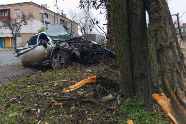 Ciddi bir trafik kazasından sonra bir yolcu arabası büyük hasar gördü. Araba, yolun kenarındaki bir ağaca çarptı. Ön tarafı tamamen tahrip etti. Ön camı kırdı ve yere enkaz ve parçalar saçtı.