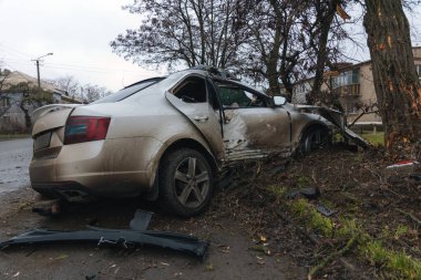 Ciddi bir trafik kazasından sonra bir yolcu arabası büyük hasar gördü. Araba, yolun kenarındaki bir ağaca çarptı. Ön tarafı tamamen tahrip etti. Ön camı kırdı ve yere enkaz ve parçalar saçtı.