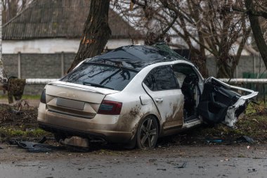 Ciddi bir trafik kazasından sonra bir yolcu arabası büyük hasar gördü. Araba, yolun kenarındaki bir ağaca çarptı. Ön tarafı tamamen tahrip etti. Ön camı kırdı ve yere enkaz ve parçalar saçtı.