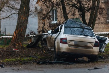 Ciddi bir trafik kazasından sonra bir yolcu arabası büyük hasar gördü. Araba, yolun kenarındaki bir ağaca çarptı. Ön tarafı tamamen tahrip etti. Ön camı kırdı ve yere enkaz ve parçalar saçtı.