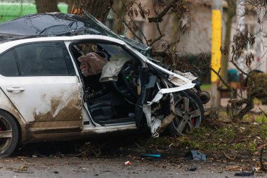 Ciddi bir trafik kazasından sonra bir yolcu arabası büyük hasar gördü. Araba, yolun kenarındaki bir ağaca çarptı. Ön tarafı tamamen tahrip etti. Ön camı kırdı ve yere enkaz ve parçalar saçtı.