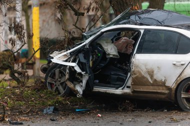 Ciddi bir trafik kazasından sonra bir yolcu arabası büyük hasar gördü. Araba, yolun kenarındaki bir ağaca çarptı. Ön tarafı tamamen tahrip etti. Ön camı kırdı ve yere enkaz ve parçalar saçtı.