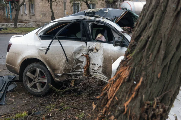 Ciddi bir trafik kazasından sonra bir yolcu arabası büyük hasar gördü. Araba, yolun kenarındaki bir ağaca çarptı. Ön tarafı tamamen tahrip etti. Ön camı kırdı ve yere enkaz ve parçalar saçtı.