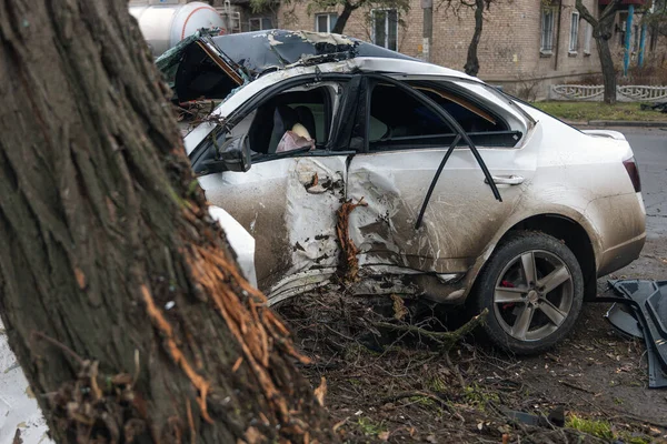 Ciddi bir trafik kazasından sonra bir yolcu arabası büyük hasar gördü. Araba, yolun kenarındaki bir ağaca çarptı. Ön tarafı tamamen tahrip etti. Ön camı kırdı ve yere enkaz ve parçalar saçtı.