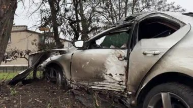 Ciddi bir trafik kazasından sonra beyaz bir yolcu arabası büyük hasar gördü. Araba, yolun kenarındaki bir ağaca çarptı. Ön tarafı tamamen tahrip etti. Ön camı kırdı ve yere enkaz ve parçalar saçtı..