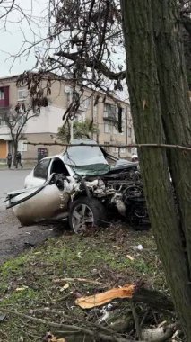 Ciddi bir trafik kazasından sonra beyaz bir yolcu arabası büyük hasar gördü. Araba, yolun kenarındaki bir ağaca çarptı. Ön tarafı tamamen tahrip etti. Ön camı kırdı ve yere enkaz ve parçalar saçtı..
