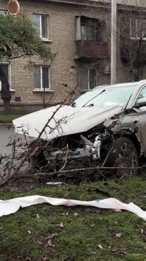 Şiddetli bir kazadan sonra, bir şehir caddesinde meydana gelen çarpışmadan sonra ön yüzünde feci hasar olan gri bir SUV. Kaput buruşmuş, lastik yerinden çıkmış, ön cam kırılmış ve kapı açık ve deforme olmuş..