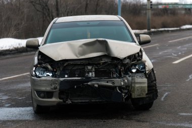 Kötü deforme olmuş bir kaput, kırık farlar ve yolda hasarlı bir radyatör ile kaza yaptıktan sonra kaza yapmış bir arabanın ön tarafında..