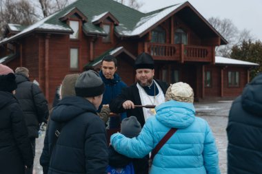 Bir Ortodoks rahibi kutsal su ayinini gerçekleştirir. Rahip kör edici bir madde kullanarak kutsal su serpiyor. Kışın geleneksel bir dini tören. Belgesel fotoğrafçılık. Suyun vaftiz töreni..