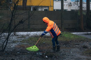 Renkli üniformalı bir kamu görevlisi konut alanını bombaladıktan sonra enkaz ve molozları vantilatörle temizliyor. Sonuçları ortadan kaldırmak ve çatışma bölgesinde düzeni sağlamak için acil servislerin çalışması.