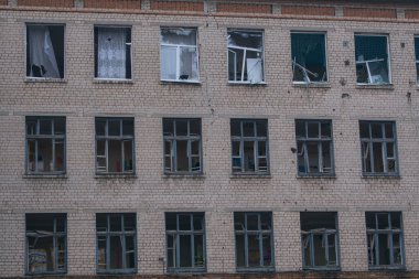 Çok katlı bir binanın tuğla perçemi. Çok sayıda kırık penceresi ve duvarları var. Görüntü, camdaki hasarı ve şok dalgasının etkilerini ayrıntılı olarak yakalar..