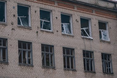 Çok katlı bir binanın tuğla perçemi. Çok sayıda kırık penceresi ve duvarları var. Görüntü, camdaki hasarı ve şok dalgasının etkilerini ayrıntılı olarak yakalar..