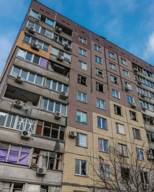 Dnipro 'daki çok katlı bir bina ciddi hasar izleri gösteriyor: kırık cam, parçalanmış balkon çerçeveleri ve parlak mavi gökyüzüne bantlanmış pencereler.