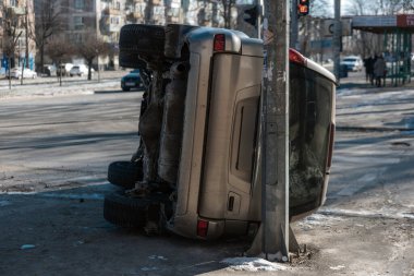 Şehir caddesinde geçirdiği bir kazadan sonra altın rengi bir SUV 'nin dikiz aynasından devrildi. Araç elektrik direğine dayanıyor. Şasi ve vücut hasarını gün ışığında gösteriyor.