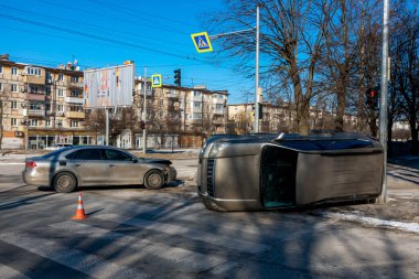 Şehir kavşağında çok araçlı bir kazanın geniş açılı görüntüsü. Yan tarafında bir trafik lambasının yanında duran altın rengi bir SUV, ön tarafında hasar olan gümüş bir sedan ise asfaltta duruyor.