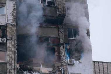 İçerideki çok katlı bir binaya yapılan grevden sonra. Fotoğrafta binanın yıkılan perileri, kırılan camları ve ağır dumanı görülüyor. İtfaiyeciler yangını söndürmek için çalışıyor; su akıntısı doğrudan...