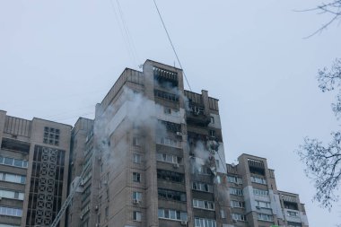 Vinç sepetindeki itfaiyeciler, büyük bir yangının ardından camlardan duman yükselirken hasarlı bir tuğla binanın tepesinde çalışıyorlar..