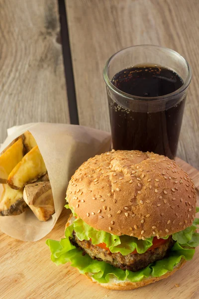 Burger, ziemniaki klinów i cola na drewnianej tablicy — Zdjęcie stockowe