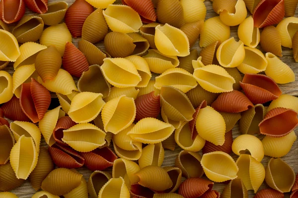 Muschelnudeln auf hölzerner Tischplatte — Stockfoto