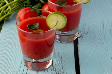 Mavi ahşap masa üzerinde bardaklarda domates gaspaço